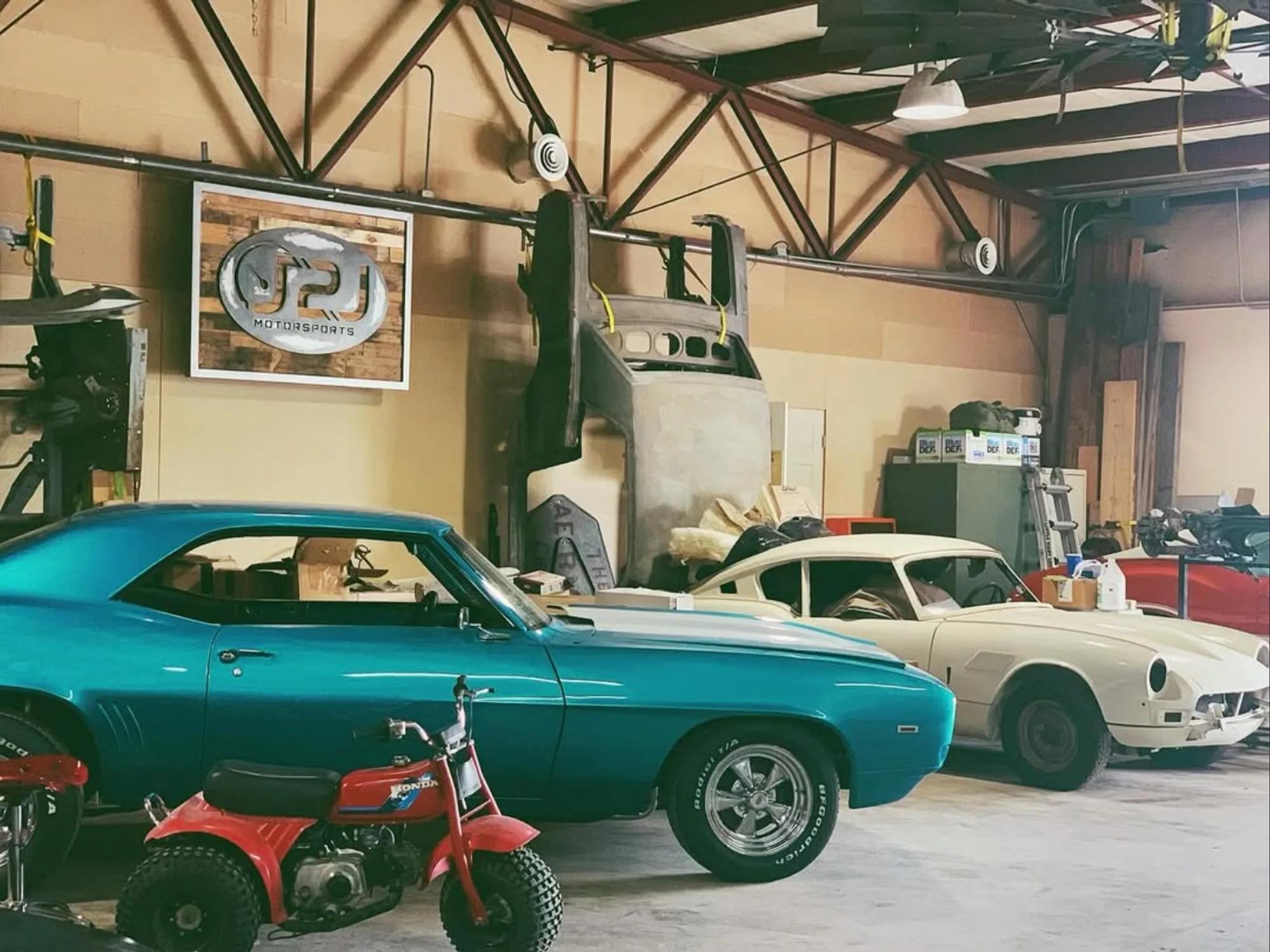 The J2J Motorsports shop floor, lined with project cars under the shop sign